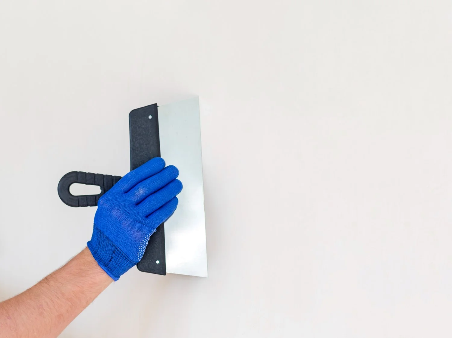 Gipser glättet eine helle Wand mit einer Kelle